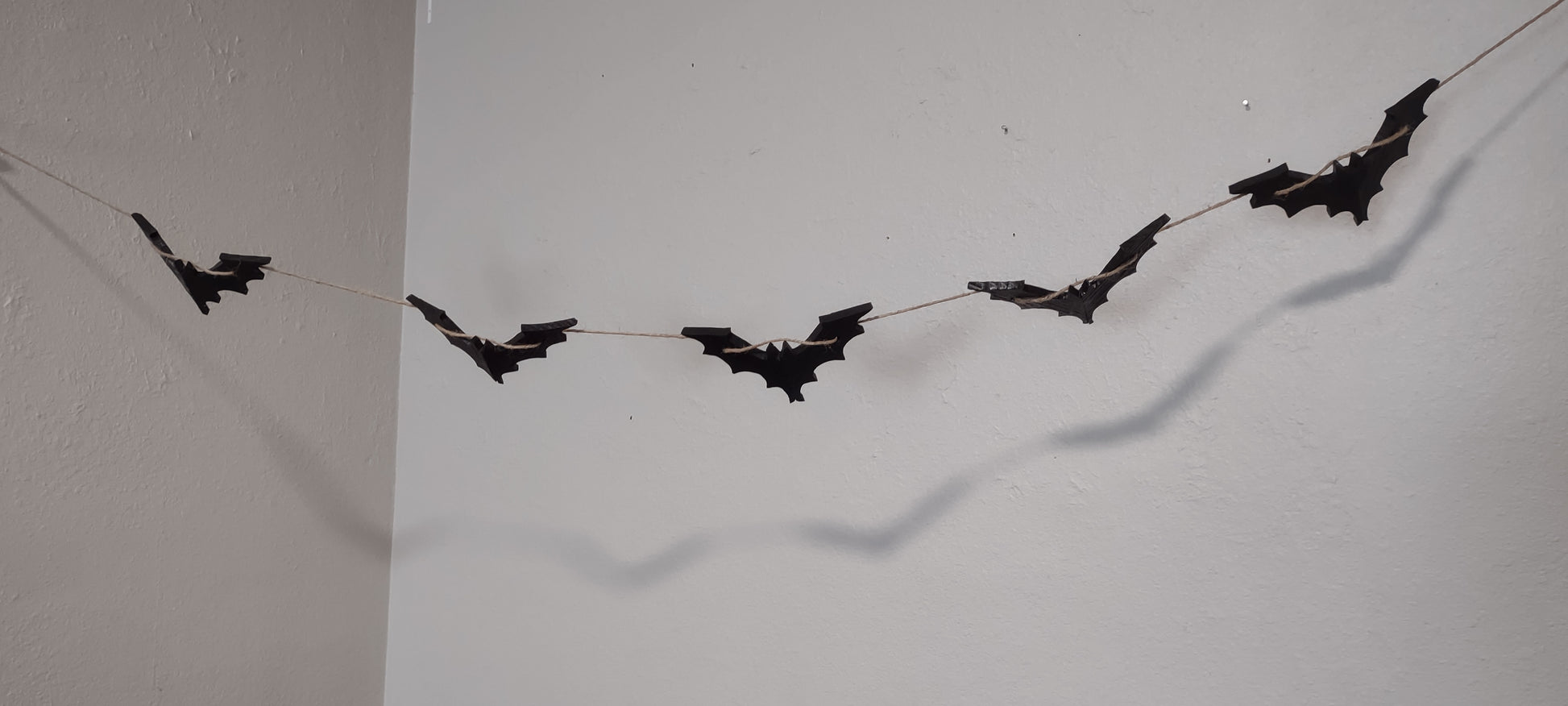 Black, wooden Halloween bat garland. Five bates on five feet of brown twine.